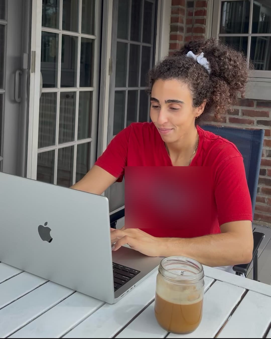 Gabrielle travaille sur un ordinateur portable dehors.